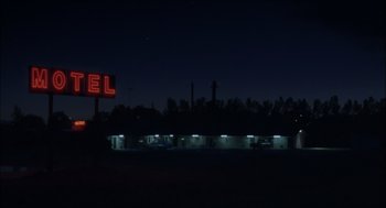 Movie still from “Brokeback Mountain” (2005), directed by Ang Lee – A motel sign lit up at night in the dark; Extreme Wide shot, Low angle