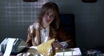 Movie still from “Brokeback Mountain” (2005), directed by Ang Lee – A woman sitting at a desk holding a piece of paper; Medium shot, Over the shoulder angle