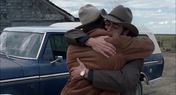 Movie still from “Brokeback Mountain” (2005), directed by Ang Lee – A man and a woman hugging in front of a blue car; Medium shot, Over the shoulder angle