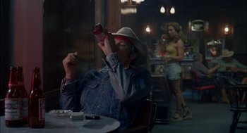 Movie still from “Brokeback Mountain” (2005), directed by Ang Lee – An older man sitting at a table drinking a soda; Wide shot, Over the shoulder angle