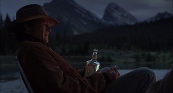 Movie still from “Brokeback Mountain” (2005), directed by Ang Lee – An older man holding a bottle of alcohol in his hand; Medium shot, Low angle