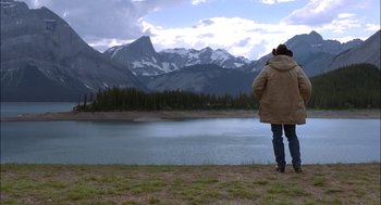 Movie still from “Brokeback Mountain” (2005), directed by Ang Lee – A person standing on the side of a lake near some mountains; Wide shot, Over the shoulder angle
