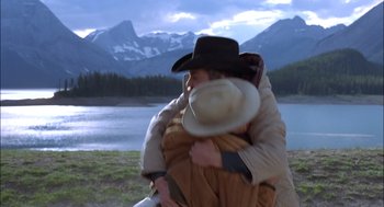 Movie still from “Brokeback Mountain” (2005), directed by Ang Lee – A man and a woman hugging in front of a lake and mountains; Medium shot, Low angle