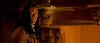 Movie still from “Brotherhood of the Wolf” (2001), directed by Christophe Gans – A man standing next to a pillar in a room; Close Up shot, Low angle