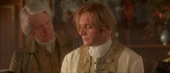 Movie still from “Brotherhood of the Wolf” (2001), directed by Christophe Gans – A person wearing a suit and tie; Close Up shot, Over the shoulder angle