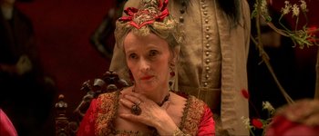 Movie still from “Brotherhood of the Wolf” (2001), directed by Christophe Gans – An older woman in a red and gold dress; Close Up shot, Over the shoulder angle