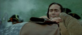 Movie still from “Brotherhood of the Wolf” (2001), directed by Christophe Gans – A man with long black hair is holding a leather bag over his shoulder; Close Up shot, Low angle