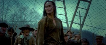 Movie still from “Brotherhood of the Wolf” (2001), directed by Christophe Gans – A man with long black hair standing in front of a group of people; Medium shot, Low angle