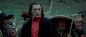 Movie still from “Brotherhood of the Wolf” (2001), directed by Christophe Gans – A man in a red and black jacket standing next to a man in a black coat; Medium shot, Low angle