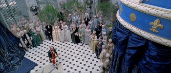 Movie still from “Brotherhood of the Wolf” (2001), directed by Christophe Gans – A group of people standing around a room; Extreme Wide shot, Overhead angle