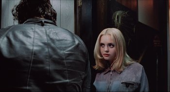 A woman with blonde hair looking into a mirror