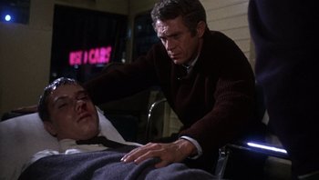 Movie still from “Bullitt” (1968), directed by Peter Yates – A man is touching a man's face in a room; Medium shot, Low angle