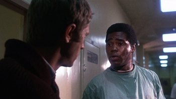 Movie still from “Bullitt” (1968), directed by Peter Yates – A man talking to another man in a room; Close Up shot, Low angle