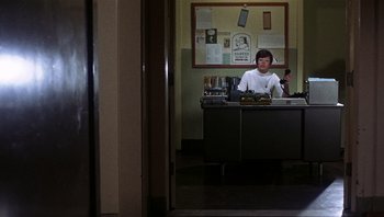 Movie still from “Bullitt” (1968), directed by Peter Yates – A person sitting at a desk in a room; Wide shot, High angle