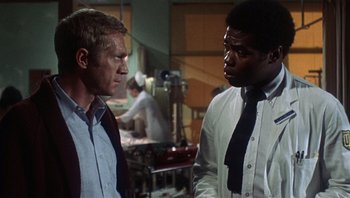 Movie still from “Bullitt” (1968), directed by Peter Yates – Two men are talking to each other in a room; Medium shot, Over the shoulder angle