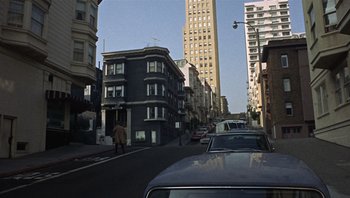 Movie still from “Bullitt” (1968), directed by Peter Yates – A car driving down a street next to tall buildings; Extreme Wide shot, Low angle