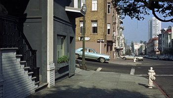 Movie still from “Bullitt” (1968), directed by Peter Yates – A car parked on the side of the road near a building; Wide shot, High angle