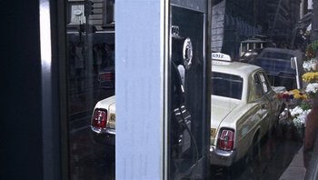 Movie still from “Bullitt” (1968), directed by Peter Yates – A view of a taxi cab and a car through a glass window; Wide shot, Over the shoulder angle