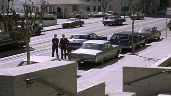 Movie still from “Bullitt” (1968), directed by Peter Yates – Two men standing on the side of the street; Extreme Wide shot, High angle