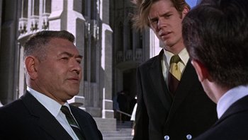 Movie still from “Bullitt” (1968), directed by Peter Yates – Two men wearing suits and ties and one is holding a bird in his hand; Medium shot, Low angle
