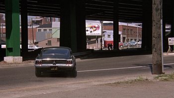 Movie still from “Bullitt” (1968), directed by Peter Yates – A car parked on the side of a road under a bridge; Extreme Wide shot, Low angle