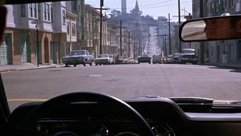 Movie still from “Bullitt” (1968), directed by Peter Yates – A view from inside a car looking out the window at a busy street; Wide shot, High angle
