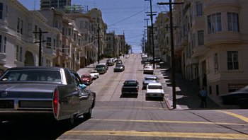 Movie still from “Bullitt” (1968), directed by Peter Yates – Cars are driving down a street in a city; Extreme Wide shot, High angle