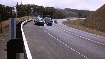 Movie still from “Bullitt” (1968), directed by Peter Yates – Two cars are driving down the road on a highway; Extreme Wide shot, High angle