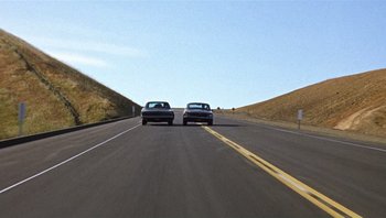Movie still from “Bullitt” (1968), directed by Peter Yates – A couple of cars driving down a street; Extreme Wide shot, High angle