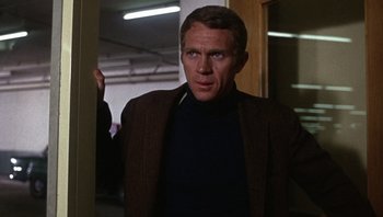 Movie still from “Bullitt” (1968), directed by Peter Yates – A man standing in a room wearing a jacket; Medium shot, Over the shoulder angle