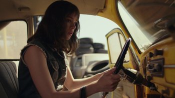 Movie still from “Bumblebee” (2018), directed by Travis Knight – A young woman is driving a car in the street; Close Up shot, Low angle