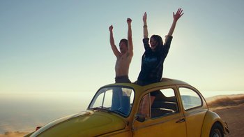 Movie still from “Bumblebee” (2018), directed by Travis Knight – A man and a woman standing on the hood of an old car; Wide shot, Low angle