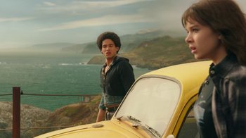 Movie still from “Bumblebee” (2018), directed by Travis Knight – Two young men standing next to a yellow car; Medium shot, Low angle