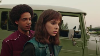 Movie still from “Bumblebee” (2018), directed by Travis Knight – A young woman standing next to a young man in front of a green van; Medium shot, Over the shoulder angle