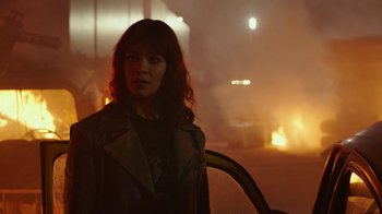 Movie still from “Bumblebee” (2018), directed by Travis Knight – A woman standing next to a car on a city street; Medium shot, Over the shoulder angle