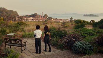 Movie still from “Bumblebee” (2018), directed by Travis Knight – Two people looking out at the water from a walkway; Extreme Wide shot, Over the shoulder angle