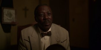 Movie still from “Fargo” (2014), created by Noah Hawley – A man wearing a suit and bow tie; Close Up shot, Low angle