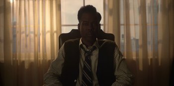 Movie still from “Fargo” (2014), created by Noah Hawley – A man sitting in an office chair in front of a window; Medium shot, Low angle