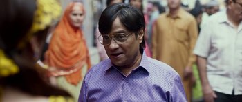 A man in a purple shirt is looking at the camera