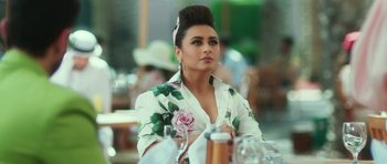 A woman sitting at a table with a rose in front of her face