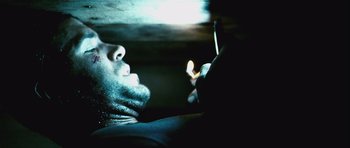 Movie still from “Buried” (2010), directed by Rodrigo Cortés – A man looking at his cell phone in a dark room; Close Up shot, Low angle