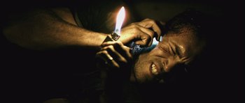 Movie still from “Buried” (2010), directed by Rodrigo Cortés – A man is holding a candle while using a cell phone; Close Up shot, High angle