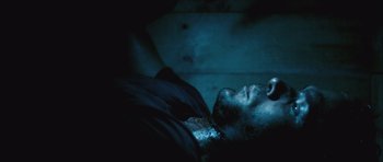 Movie still from “Buried” (2010), directed by Rodrigo Cortés – A man laying on the ground in a dark room; Extreme Close Up shot, Overhead angle