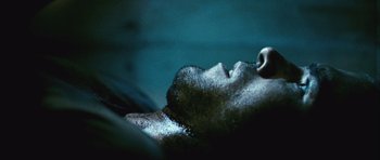 Movie still from “Buried” (2010), directed by Rodrigo Cortés – A man laying on his back with his eyes closed; Extreme Close Up shot, Overhead angle