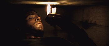 Movie still from “Buried” (2010), directed by Rodrigo Cortés – A man looking at a candle in a dark room; Close Up shot, Low angle