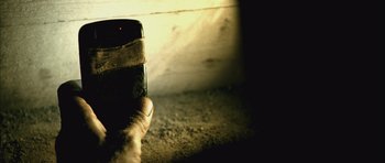 Movie still from “Buried” (2010), directed by Rodrigo Cortés – A person holding a cell phone in their hand; Extreme Close Up shot, Overhead angle