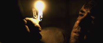 Movie still from “Buried” (2010), directed by Rodrigo Cortés – A hand holding a lit candle in a dark room; Extreme Close Up shot, High angle