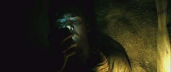 Movie still from “Buried” (2010), directed by Rodrigo Cortés – A man with his eyes closed looking at his cell phone; Close Up shot, Overhead angle