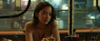 A woman sitting at a table holding a glass