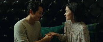 A man and a woman sitting on a couch holding hands